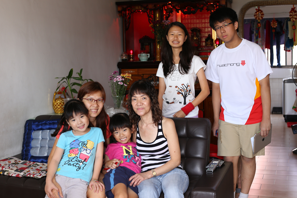 Volunteers Joshua (right standing) and Cassia (left standing) sharing stories with Mdm Lim (seated right) and family